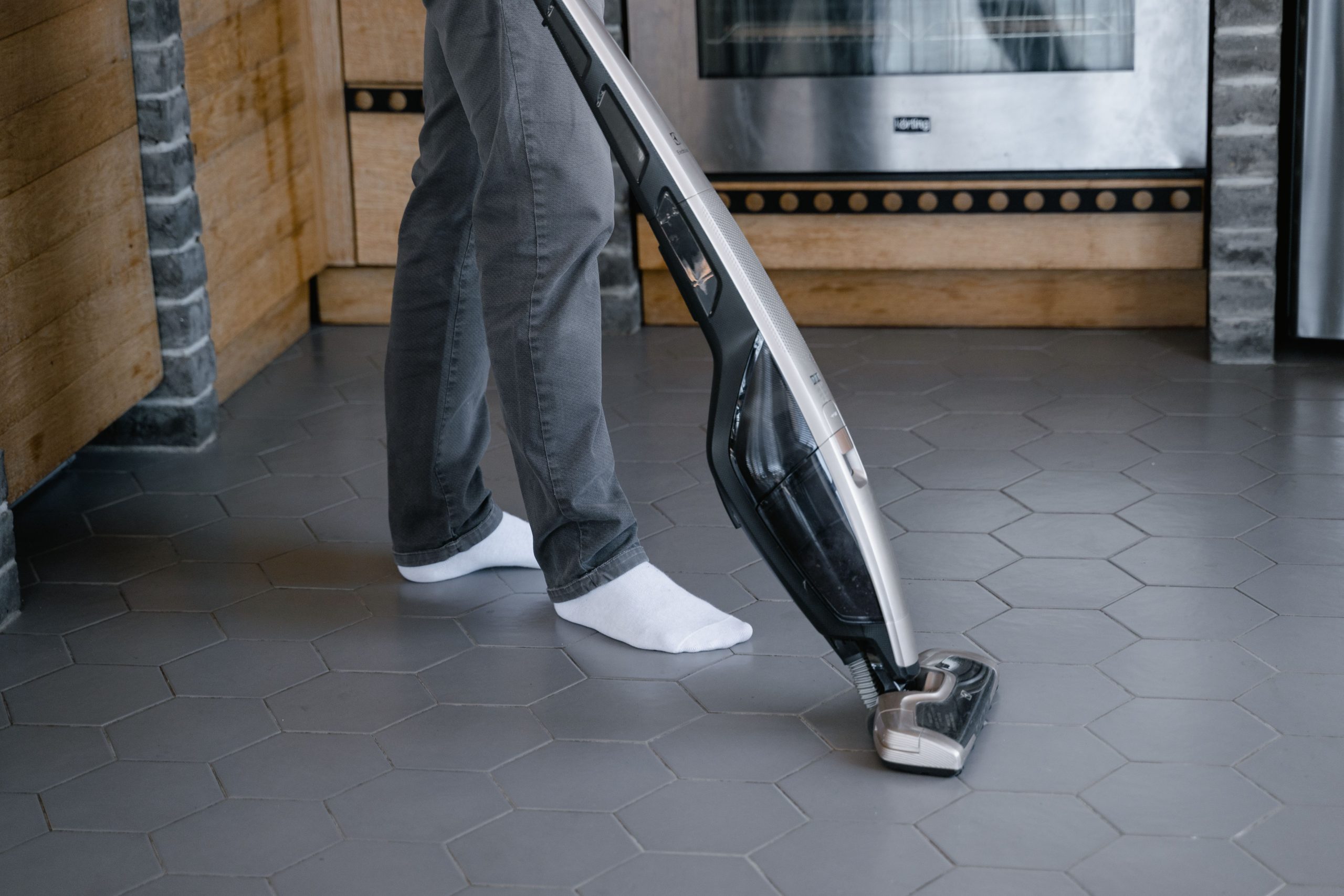 Personne nettoyant le carrelage avec un aspirateur