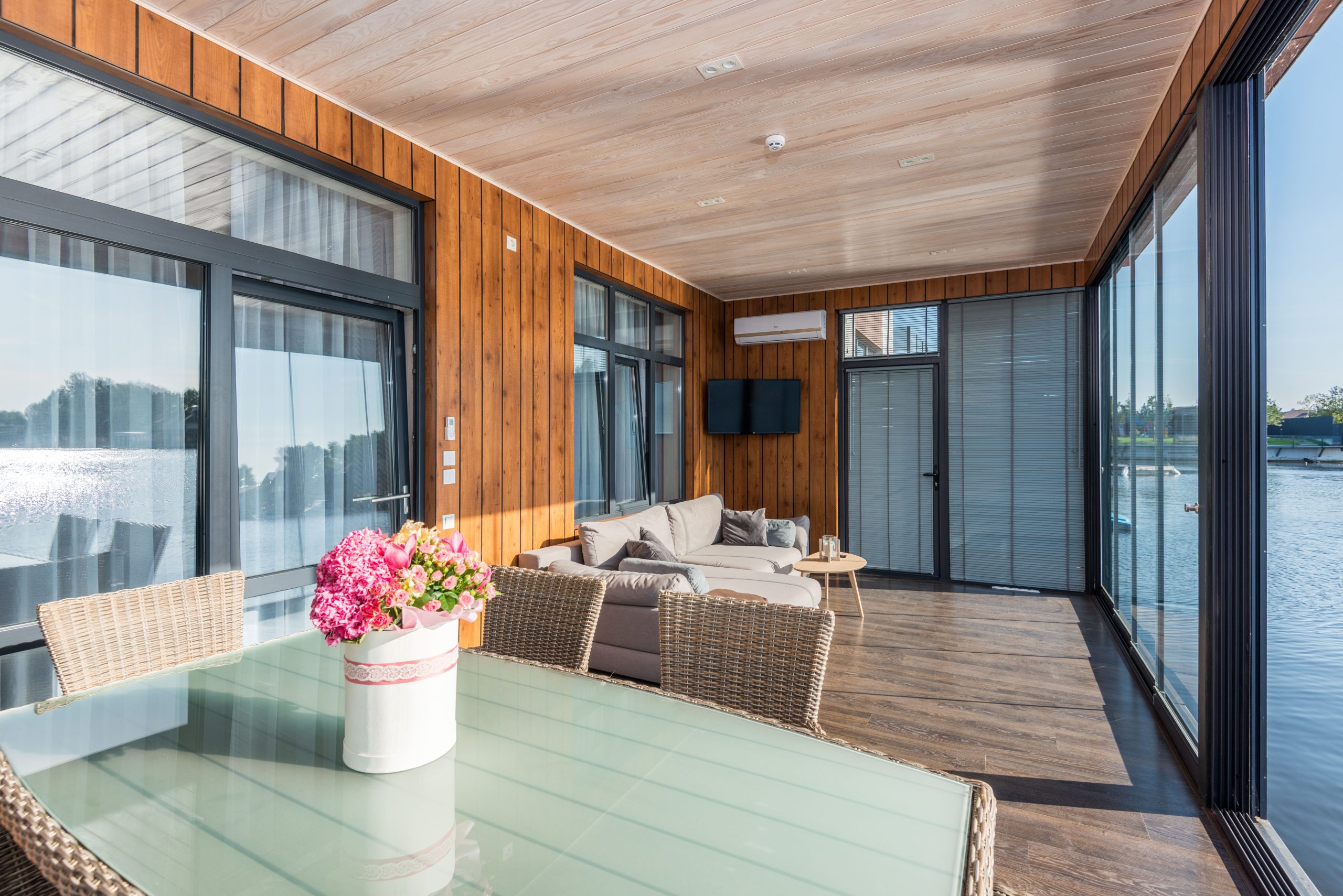Véranda ensoleillée avec mobilier rotin et fleurs colorées